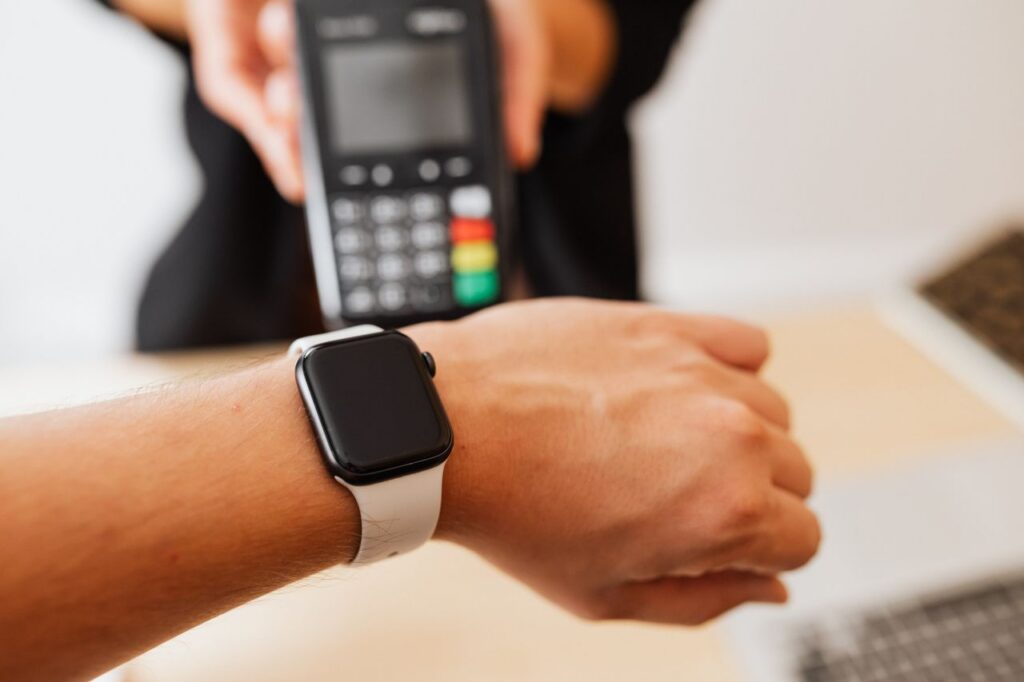 Person making a contactless payment using a smartwatch at a cashless checkout counter.