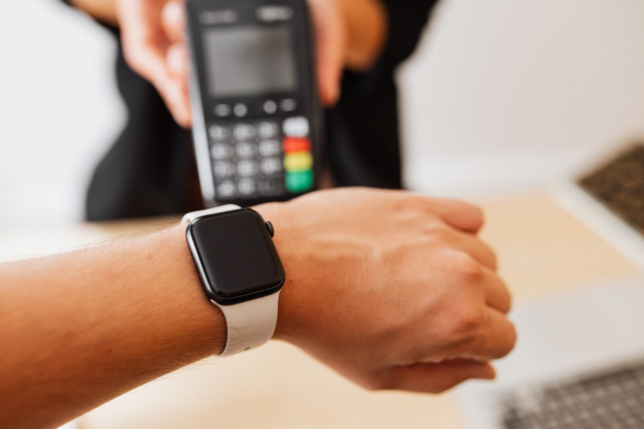 Person making a contactless payment using a smartwatch at a cashless checkout counter.